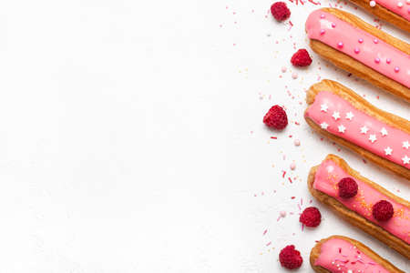 Set of delicious eclairs with pink raspberry glaze and sugar sprinkles on white background.の写真素材