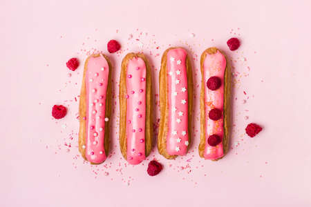 Creative layout made of eclairs with pink glaze on pink background. Monochrome Food concept.の写真素材