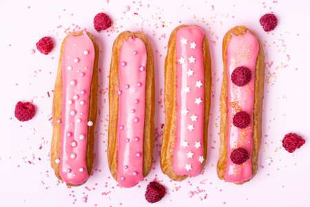 Creative layout made of eclairs with pink glaze on white background. Food concept.の写真素材