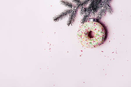 Christmas creative background. Christmas ball made of decorated donut hanging on Christmas tree branch.の写真素材