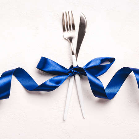 Christmas Minimal table setting with classic blue ribbon on white stone background.