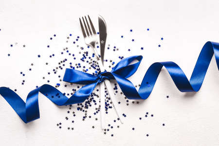 Christmas cutlery decorated classic blue ribbon and stars confetti on white background.の写真素材