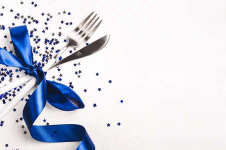 Christmas table setting decorated with phantom blue ribbon and stars confetti on white background.の写真素材