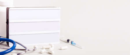 Medicine treatment concept. Empty Lightboard, stethoscope, pills and syringes. Banner format