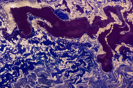 Acrylic Fluid Art. Purple Waves Pattern with Gold sparkles on blueの写真素材