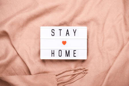 Stay home concept. STAY HOME written on light board on cozy peach plaid.の写真素材