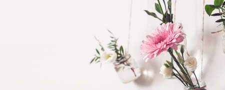 Reuse glass jars for home decor. Beautiful flowers hang on white wall.の写真素材