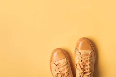 Yellow mustard sneakers on orange background. Minimal Spring summer fashion concept.
