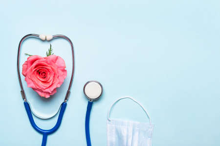 Pink rose heart, stethoscope and protective mask on blueの写真素材