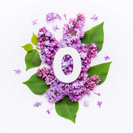 Paper number zero on background of lilac flowers. Minimal creative Layout with natural elements for your design.の写真素材