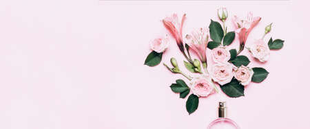 Women's perfume bottle and roses flowers on pink background. Banner format with copy space.
