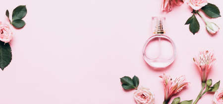 Women's perfume bottle and roses flowers on pink background. Banner format with copy space.