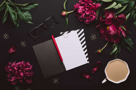 Female Home office desk. Elegant Workspace with notebook, accessories, coffee cup and peony flowers...