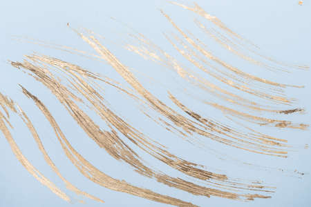 Abstract Gold potal brush strokes on blue pastel paper background or texture.