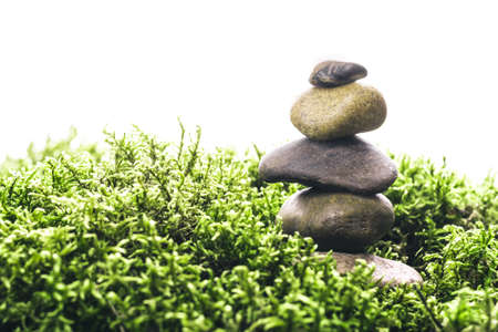 Stack of zen stones in green moss on white background. Natural backdrop for your design.の写真素材