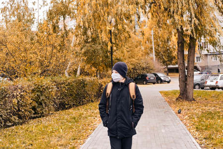 Schoolboy in a protective mask goes to school along an empty street.. New normalの写真素材
