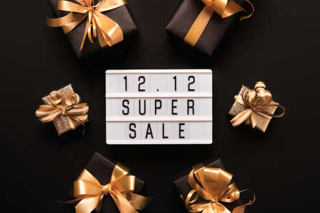 Lightbox with text SUPER SALE and golden gift boxes on black background. Double 12 Mega sales day flat lay promotion composition.の写真素材