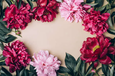 Beautiful peonies flowers frame on beige champagne background. Spring or summer floral backgroundの写真素材