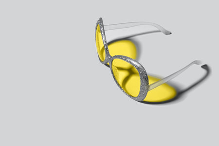 Trending colors of 2021. Plastic sunglasses with silver sparkles frame and yellow glasses. Yellow...
