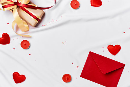 Romantic concept. Valentines day background. Red envelope, Gift box and hearts on white silk sheetの写真素材