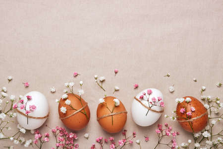 Easter eggs with natural flowers decor on linen background. Zero Waste Easter Concept in neutral...