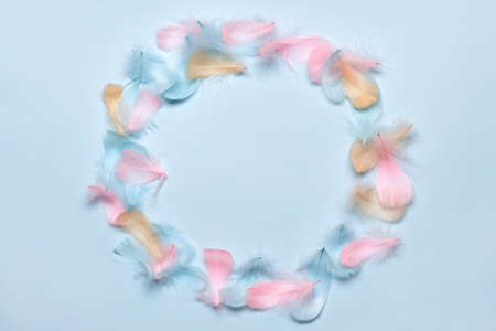 Happy easter greeting card template. Round frame made of colorful feathers on pastel blue...