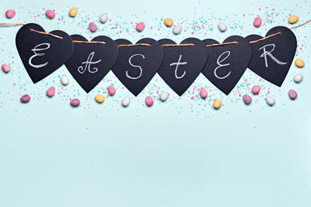 Happy easter greeting card. Garland with Easter word and chocolate eggs in sugar glaze on blue background. Flat layの写真素材