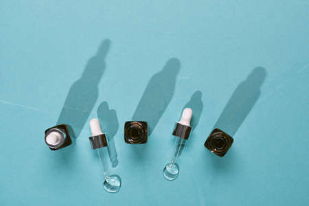 Amber glass bottle of cosmetic liquid transparent gel on blue background. Copy space and trendy long shadowsの写真素材