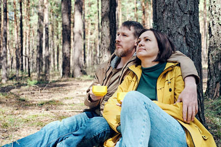 pensive middle-aged couple is resting in a coniferous forest. Local travel conceptの写真素材