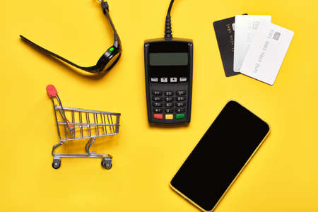 POS payment terminal, watch, bank cards and smartphone on yellow. Minimal financial service concept....