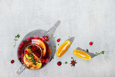 Immunity boosting drink. Winter Tea with cranberries, orange, hibiscus and spices in glass teapot on white tableの写真素材