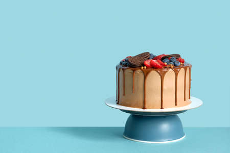 Chocolate birthday cake with berries and cookies on blue wall table background, copy spaceの写真素材