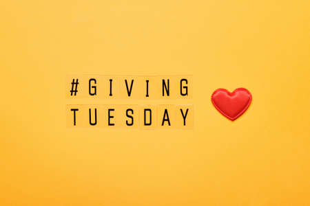 Giving Tuesday text message. Global day of charitable giving after Black Friday shopping day. Red heart on yellow backgroundの写真素材