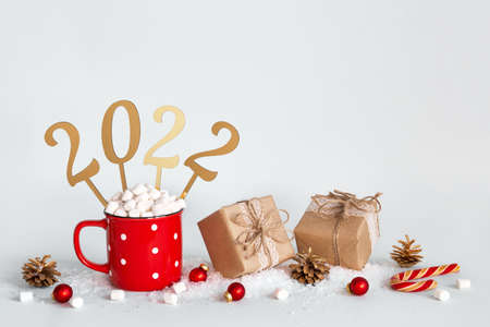 Zero waste Christmas or New Year 2022 concept. Hot chocolate in red mug, Eco friendly packaging gifts and golden numbers 2022, copy spaceの写真素材