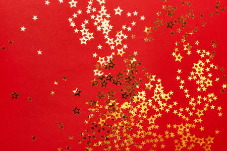 Golden stars confetti on red background. Christmas festive background