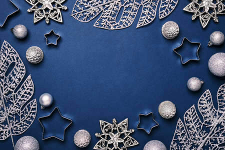 Christmas blue background. Shining silver pattern frame made of frost decorative leaves and baublesの写真素材