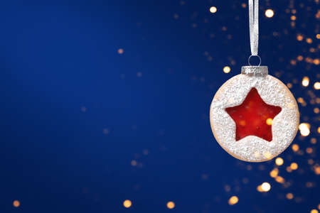 Christmas ball made of Linzer cookies hanging over pink background. Minimal Christmas backgroundの写真素材