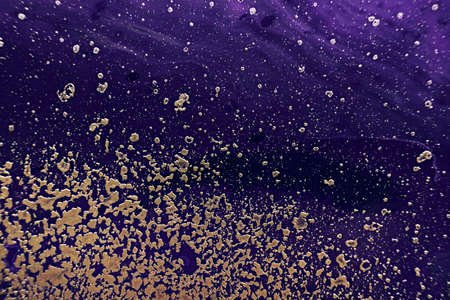 Fluid Art. Golden spray particles and purple waves on black background. Marble effect background or textureの写真素材