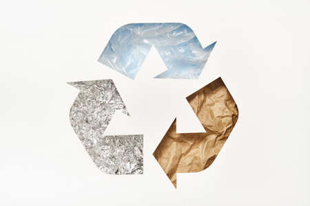 Recycle symbol made of cut paper with plastic, paper and foil on blue background. Reuse, reduce, recycle conceptの写真素材