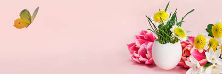 Easter creative composition. Spring flowers, Easter egg and butterflies on pink banner. Easter cardの写真素材