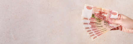 Female hand with Russian rubles five thousand banknotes. Payment in rubles concept, banner format