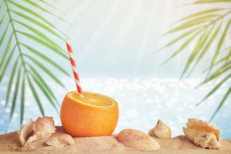 Summer travel concept with creative orange cocktail and beach. Blurred sea background with palm...
