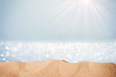 Blurred sea background with sand and sunlight. Backdrop for advertising summer travel and sun protection productsの写真素材