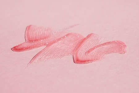 Smears of transparent shining lip gloss on a pink backgroundの写真素材