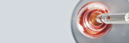 Oil or Serum bottle and pipette in petri dish on grey banner. Pink cosmetic product, selective focusの写真素材