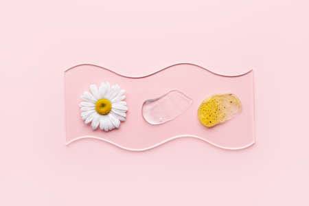 Cosmetic products with particles in glass slide on pink background. Natural skincare samples with chamomileの写真素材