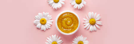 Gel cosmetic product with particles in petri dish on pink banner. Natural care cosmetic swatch with chamomileの写真素材