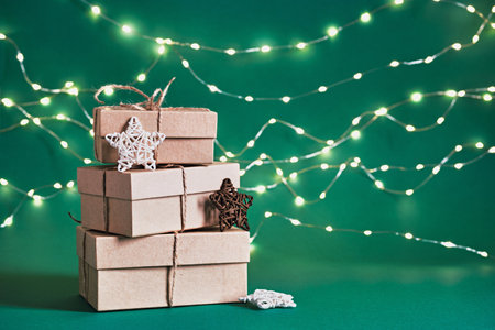 Christmas sustainable gift boxes and shining garland on green background. Christmas zero waste