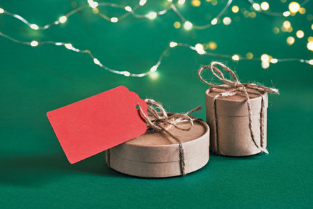 Christmas sustainable gift boxes with blank red gift card on green background. Christmas zero waste