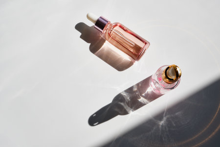 Cosmetic product bottles with rose petals and hard shadow. Skincare beauty product conceptの写真素材